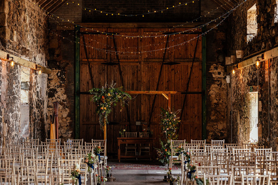 Ceremony inside The Shed at Pratis Barns, with fairy lights and wooden arch